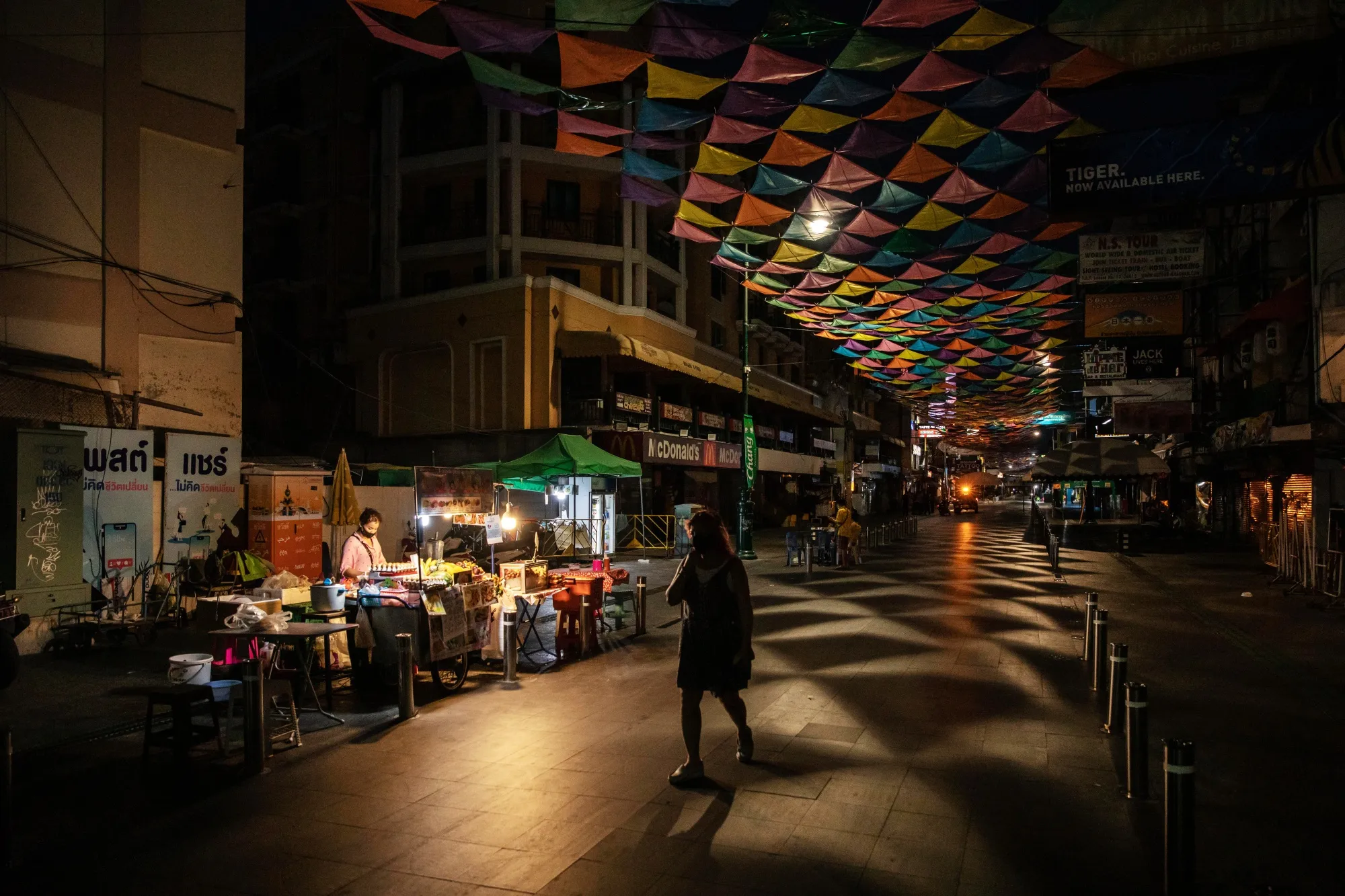 A pedestrian passes a food vendor at a deserted Khaosan Road in Bangkok on April 19.