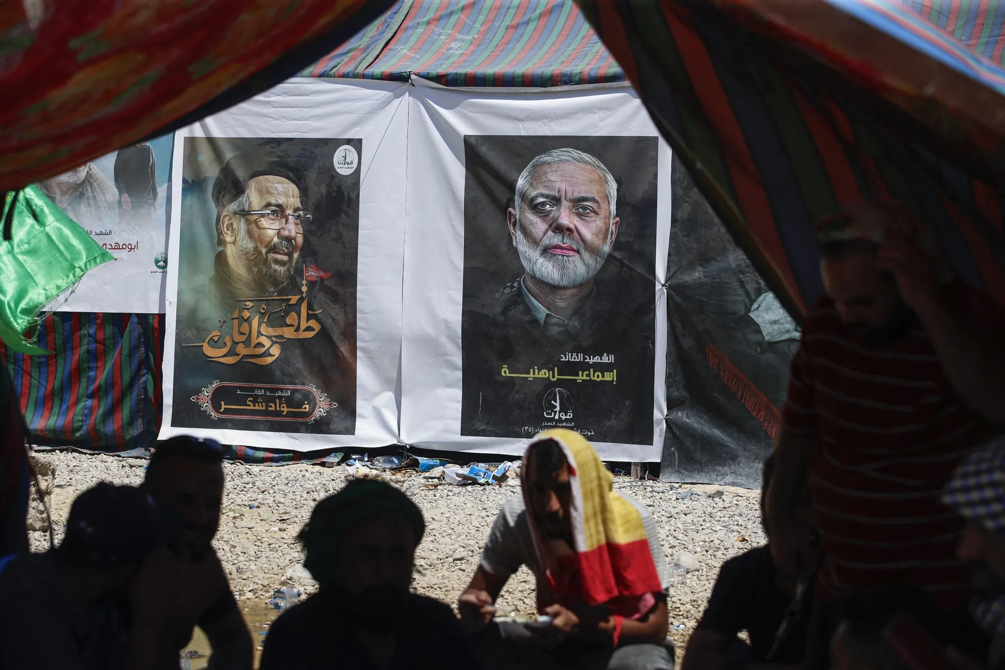 People rest in a tent across from portraits of Fuad Shukr, left,&nbsp;and Ismail Haniyeh&nbsp;at the border between Iran and Iraq, on Aug. 18.