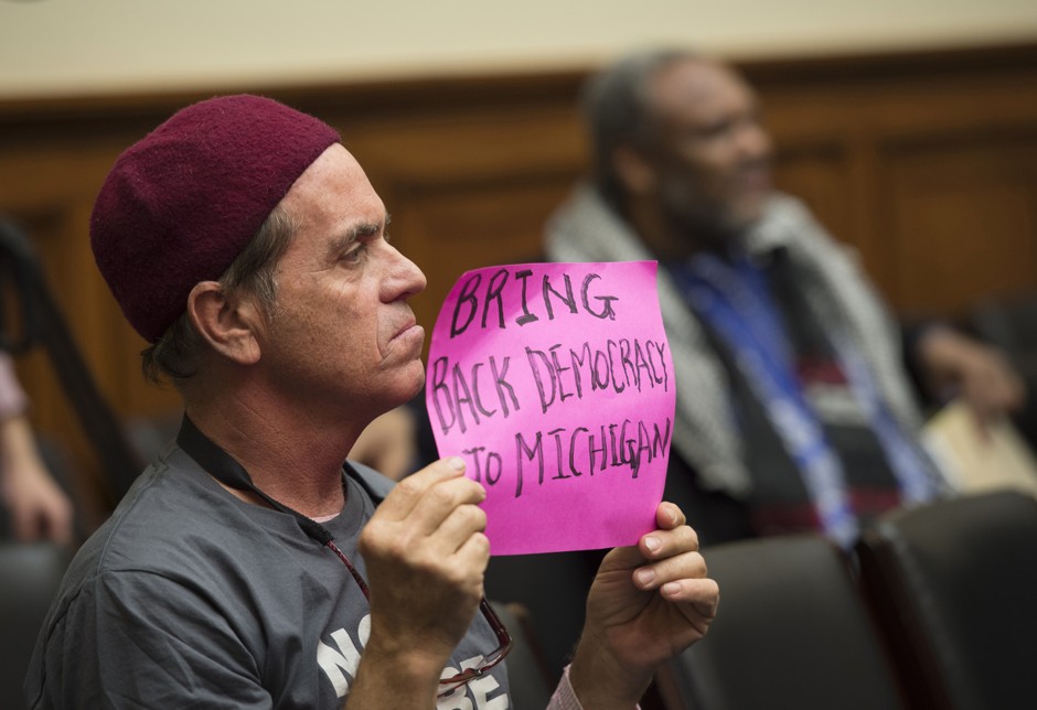 A man holds a sign during the House Oversight and Government Reform Committee hearing to examine the ongoing situation in Flint, Michigan.