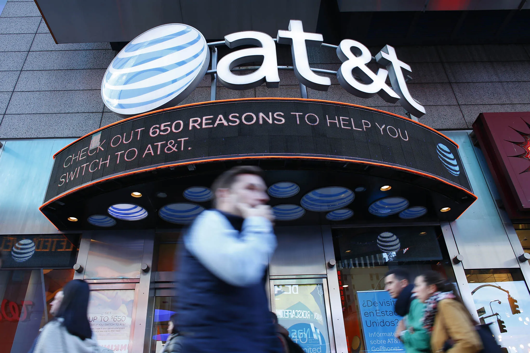 People walk past an AT&amp;T store in New York on October 23, 2016. AT&amp;T unveiled a mega-deal for Time Warner that would transform the telecom giant into a media-entertainment powerhouse positioned for a sector facing major technology changes. The stock-and-cash deal is valued at $108.7 billion including debt, and gives a value of $84.5 billion to Time Warner -- a major name in the sector that includes the Warner Bros. studios in Hollywood and an array of TV assets such as HBO and CNN. / AFP / KENA BETANCUR (Photo credit should read KENA BETANCUR/AFP/Getty Images)
