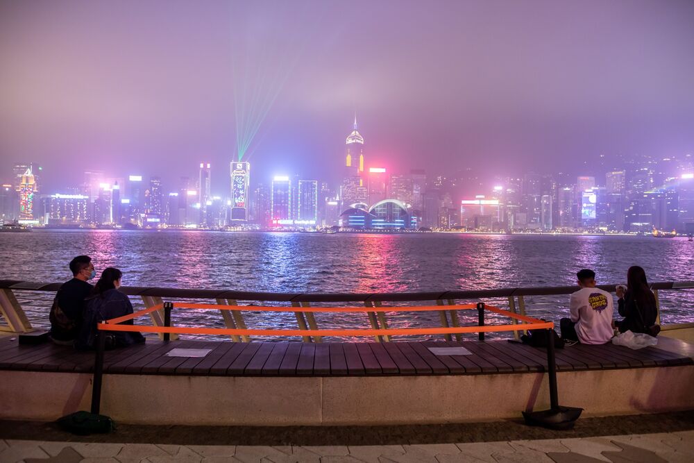 People sit beside a social distancing marker at Victoria Harbour.