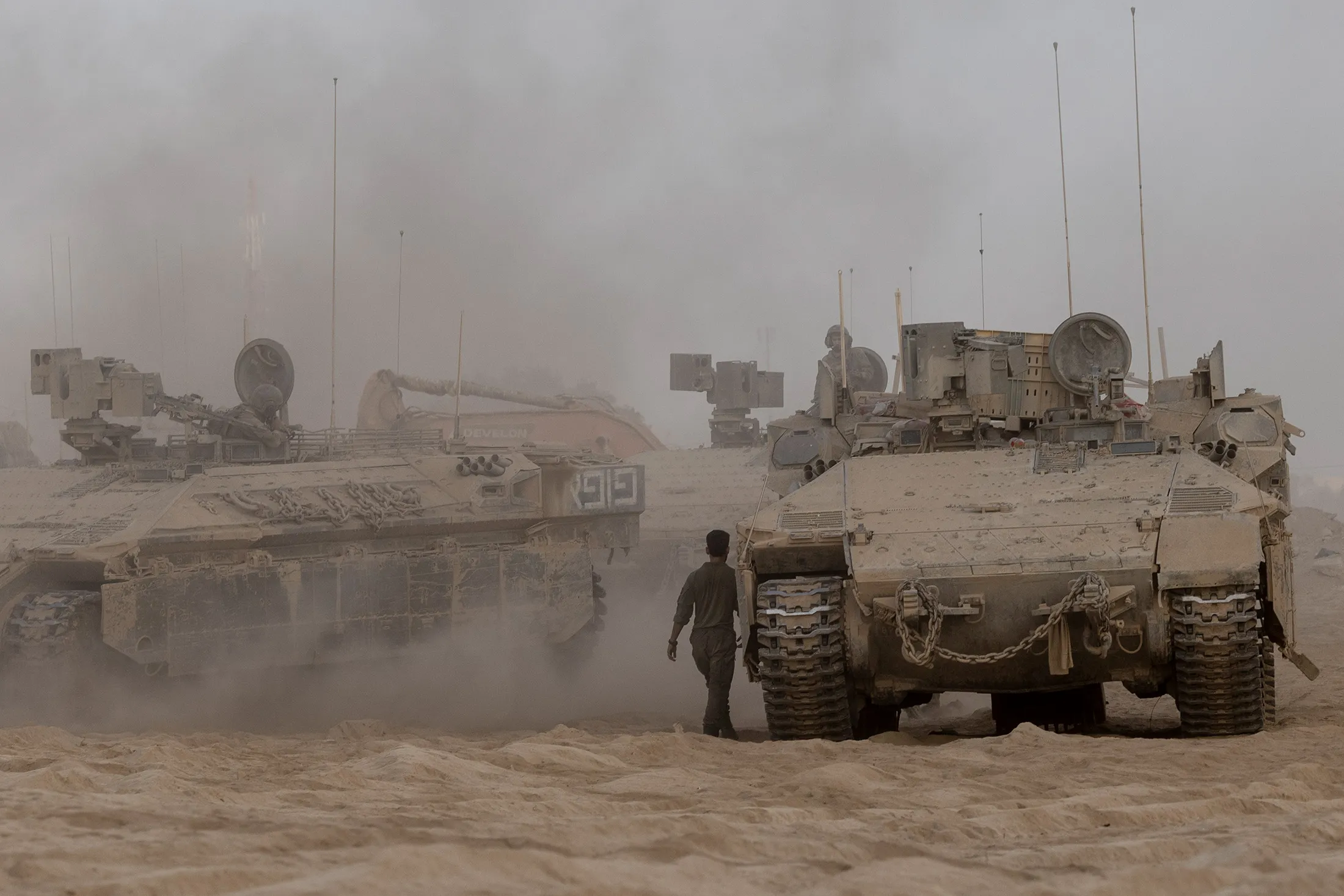 An Israeli soldier walks past armored personnel carriers near the border with the Gaza Strip in Southern Israel on Sept. 7.