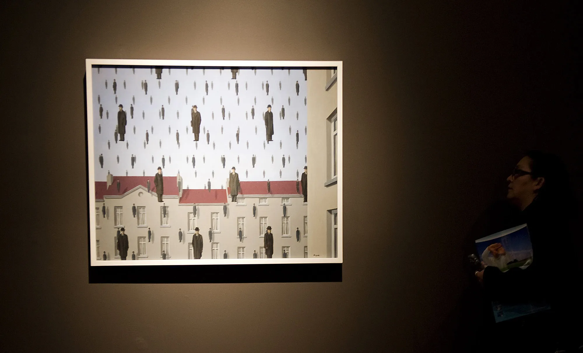 A visitor looks at "Golconda" by Rene Magritte at the Fine Arts Palace in Mexico City.