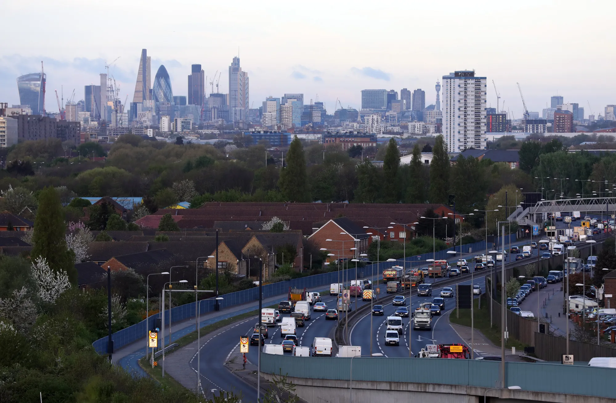 Traffic travels along the A13 dual carriageway as the City of London financial district stands on the skyline beyond in London, U.K., on Monday, April 10, 2017.