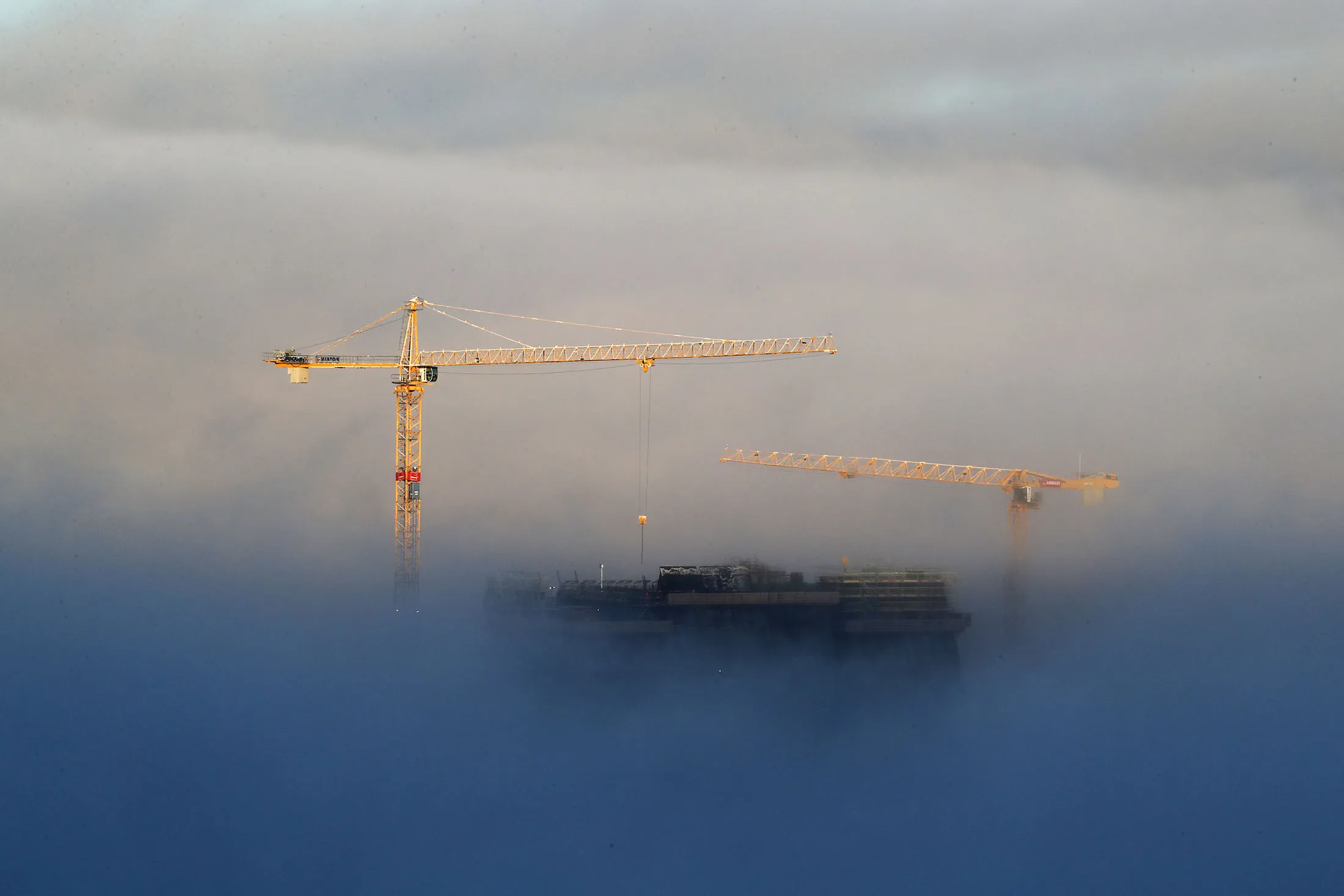 Fog surrounds cranes on a Norwegian building site. Construction,&nbsp;across its entire supply chain, is responsible for around 23% of all greenhouse gas emissions.