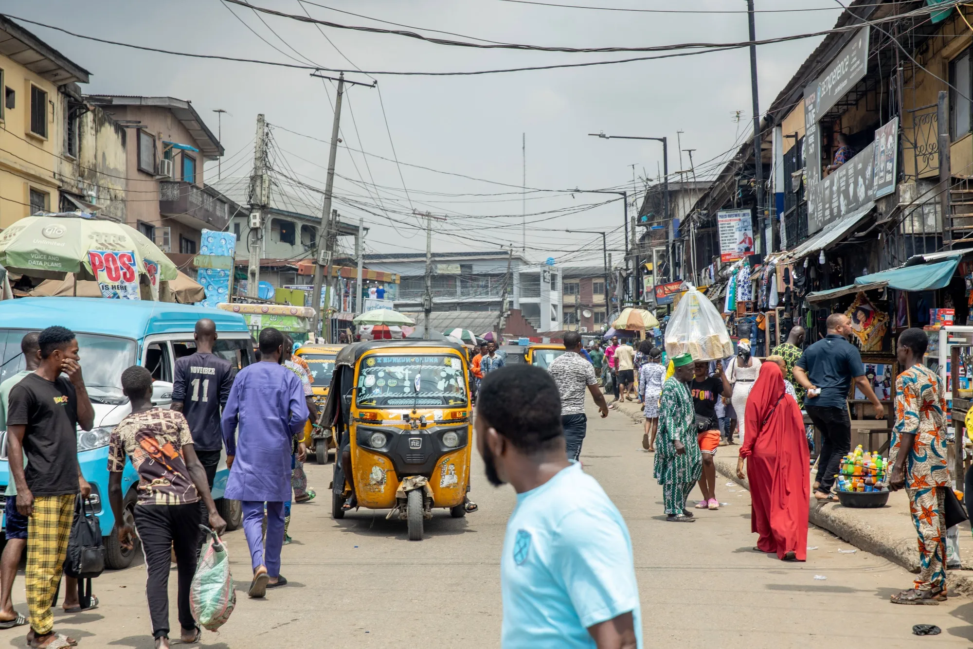 Pedestrians and auto-rickshaws make their way down a street in Lagos.