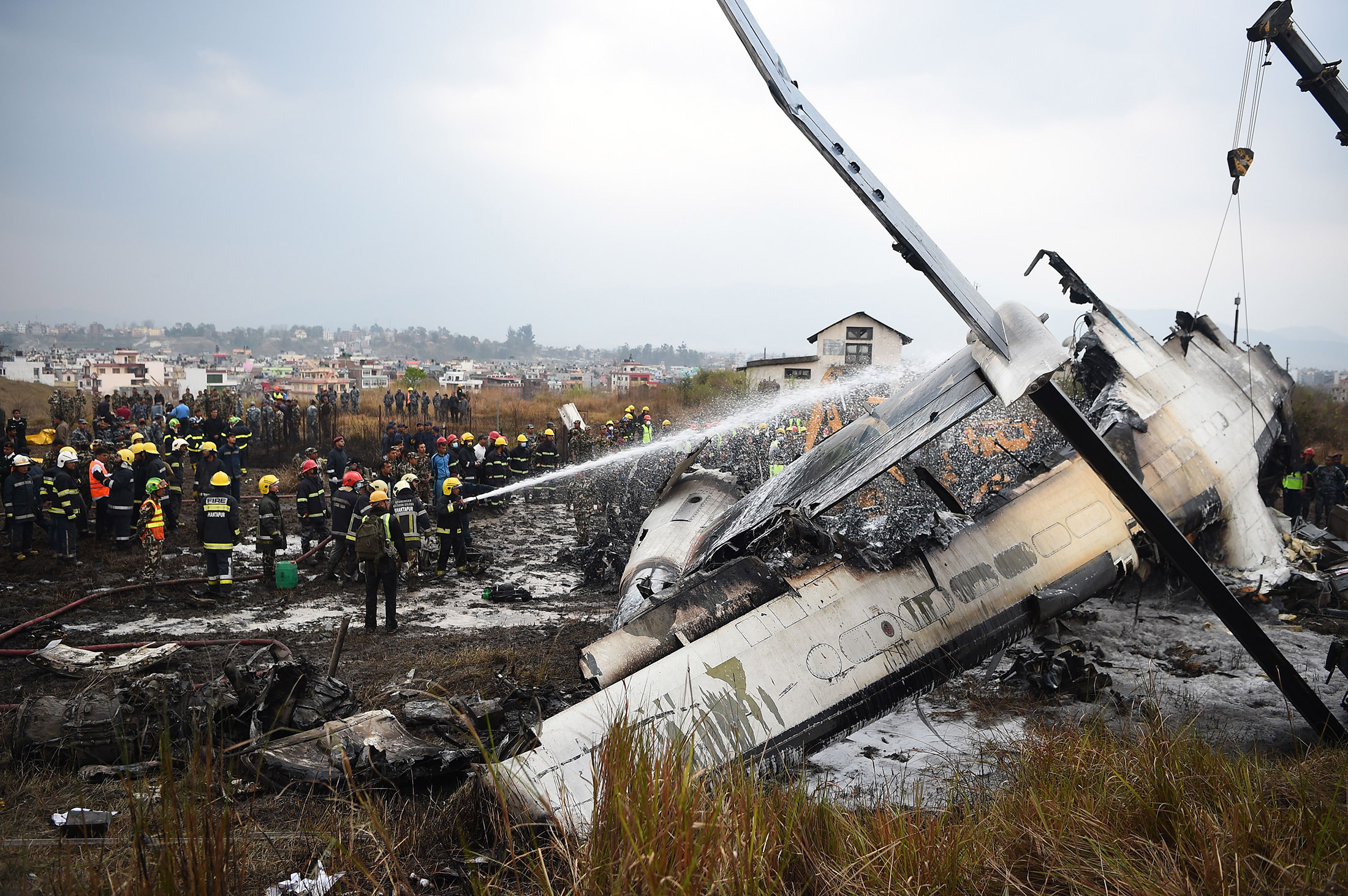 Rescue workers gather around the debris of an airplane that crashed near the international airport in Kathmandu on March 12.