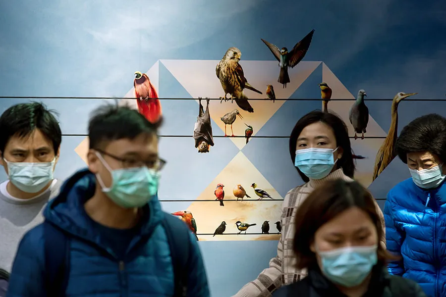 Pedestrians walk past the HSBC Holdings Plc logo displayed on a hoarding in Hong Kong, China.