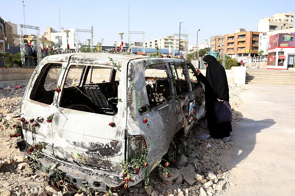 An Iranian woman checks an Iranian Red Crescent ambulance that was destroyed during an Israeli strike, displayed in Tehran on June 23, 2025.