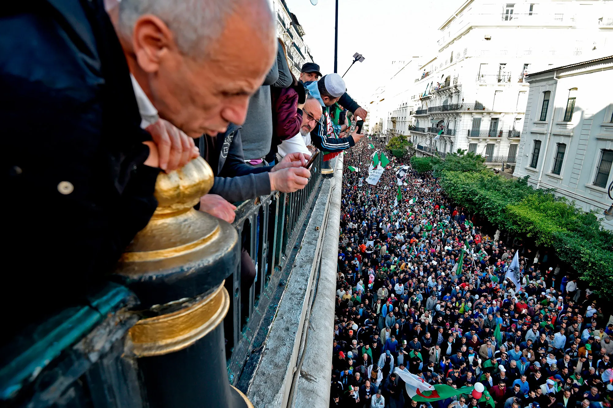 Algerians watch anti-government demonstrators march in the capital Algiers on Dec.&nbsp;6.&nbsp;