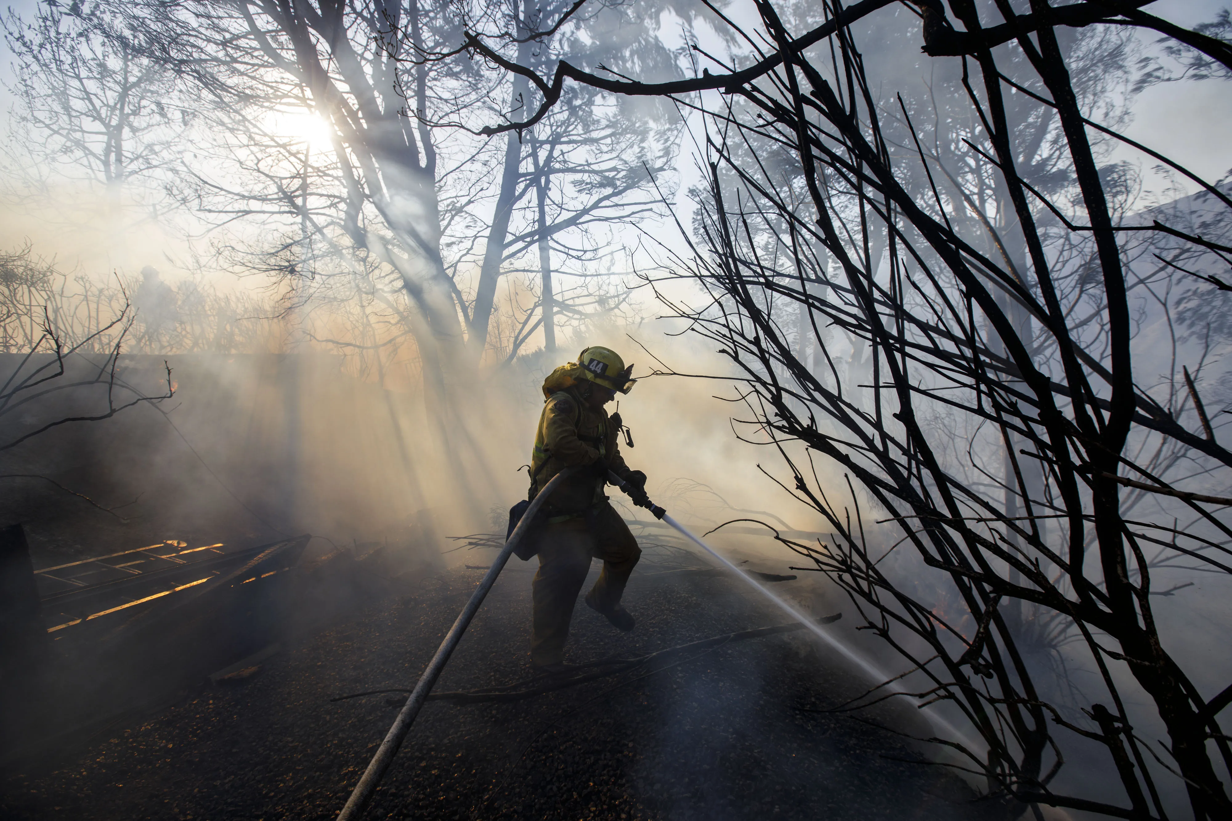 A firefighter hoses down the perimeter of a partially burned home in Los Angeles, Dec. 6, 2017.