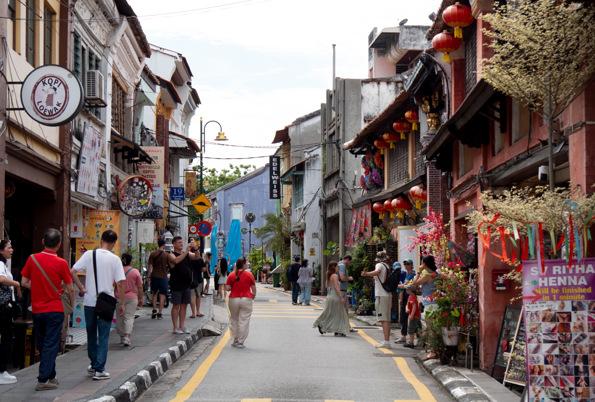 People walk down a street in George Town, Malaysia. Photographer: Stephen J. Boitano/Getty Images