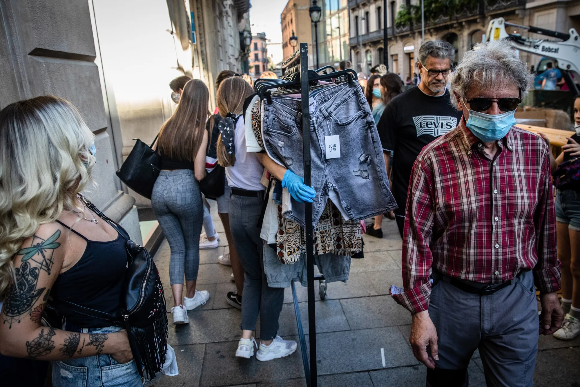 A retail assistant wearing a protective face mask and latex gloves pushes a hanger of clothing outside a Bershka store,&nbsp;in Barcelona, on June 6.
