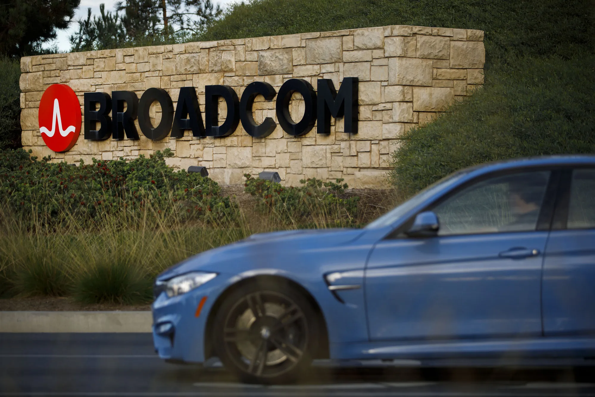 A car drives past signage displayed outside of Broadcom Ltd. headquarters in Irvine, California, U.S.