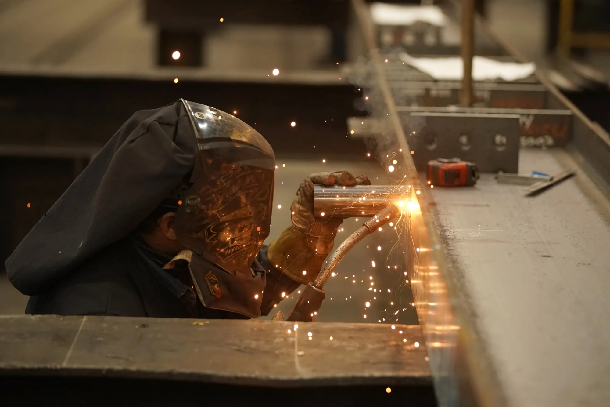 A worker welds a structural steel beam.