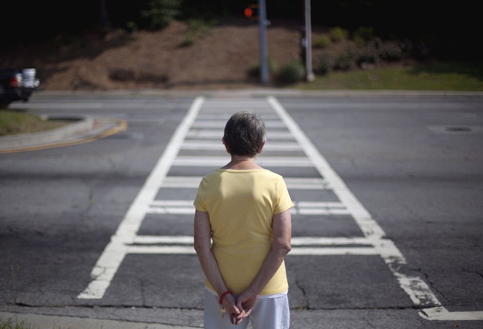 An elderly woman waits to cross an intersection near her Atlanta apartment. 