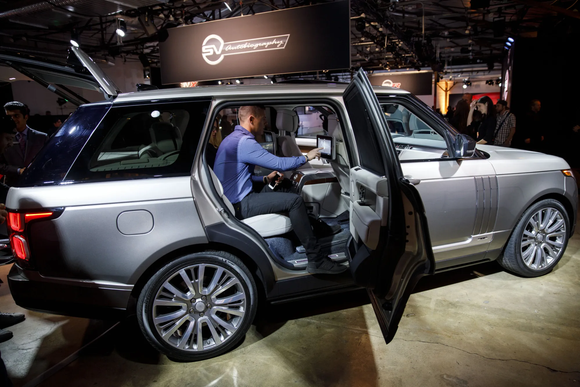 Attendees look inside a Jaguar Land Rover Automotive Plc 2018 Range Rover SVAutobiography sports utility vehicle (SUV) during a reveal event in Los Angeles, California, U.S., on Tuesday, Nov. 28, 2017. During the Los Angeles Auto Show, Land Rover will show several new editions from its Special Vehicle Operations factory, including the Range Rover SVAutobiography and the 2018 Range Rover Sport SVR and plug-in hybrid.