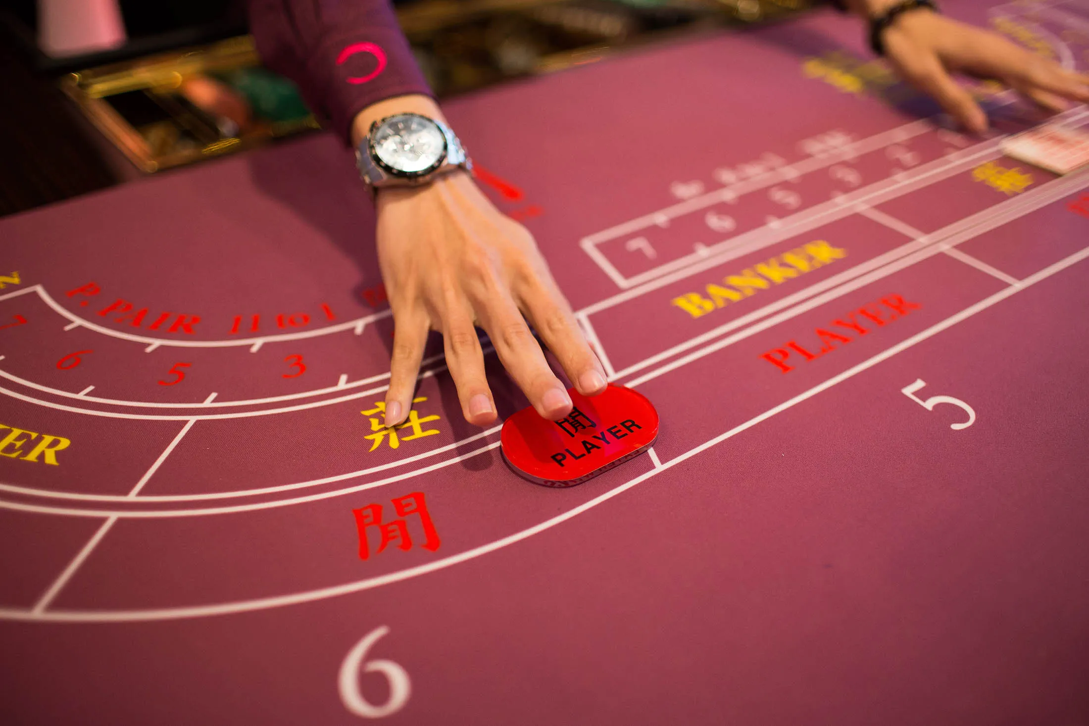 A croupier arranges a player's button on a baccarat table inside the Broadway Macau casino.

