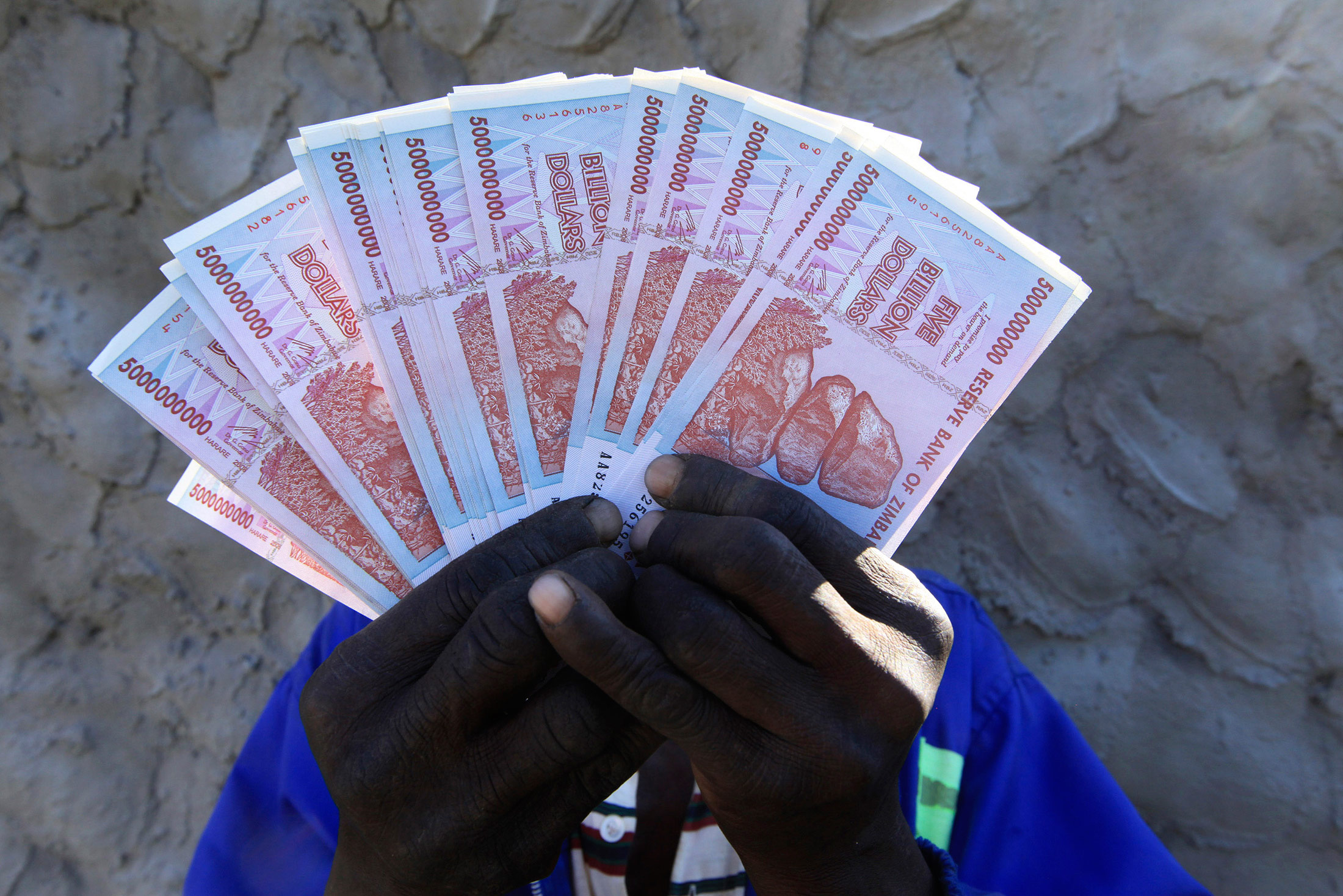 A man holds a handful of 5 Billion Zimbabwean dollar notes, in Harare.
