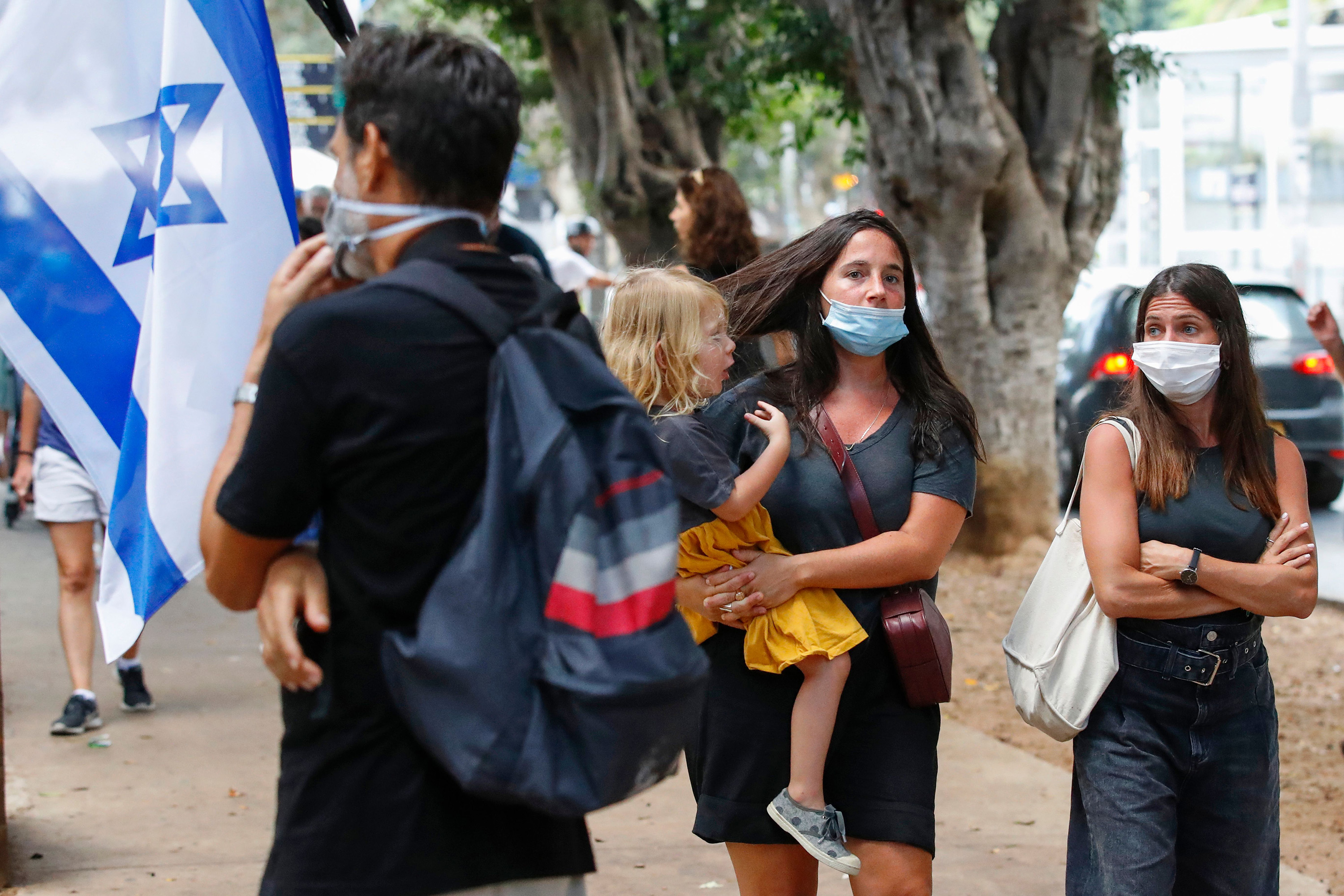People, wearing protective masks due to the Covid-19 pandemic, walk in&nbsp;Tel Aviv on July 12.