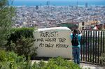 A tourist takes a picture of the city's panorama as he stands next to a wall graffiti reading at Park Guell in Barcelona on Aug. 10.
