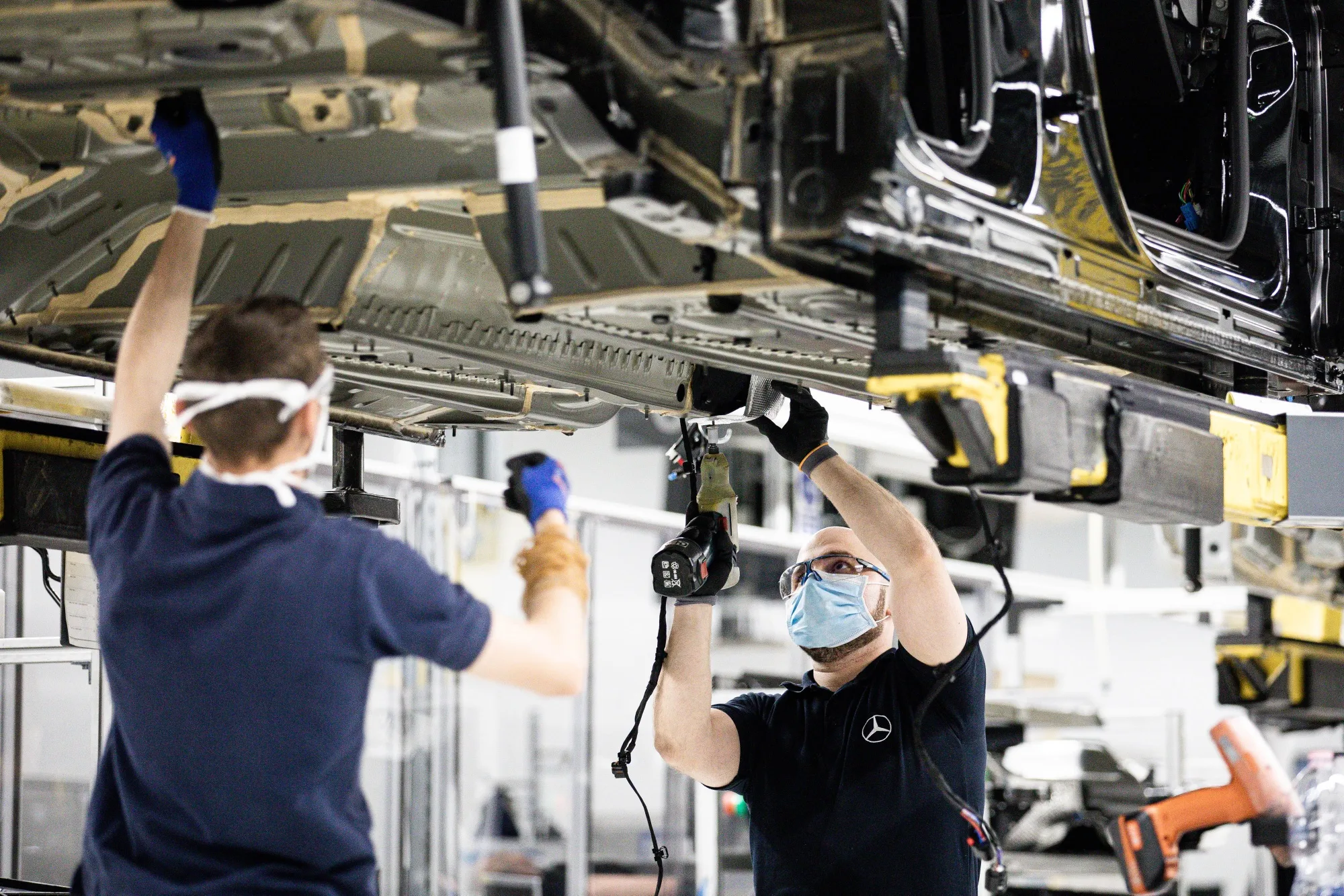 Workers affix parts to the underside of an automobile at the&nbsp;Mercedes-Benz AG automobile plant in Kecskemet, Hungary, on&nbsp;May 7.