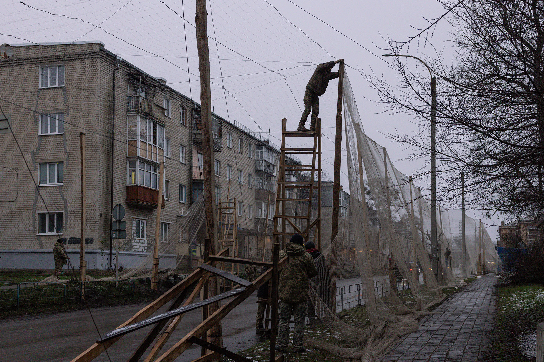 Members of the Ukranian Armed Forces install anti-drone nets in the city center of Izyum, Kharkiv region, Ukraine, on Dec. 10, 2025. Photographer: Diego Fedele/Getty Images