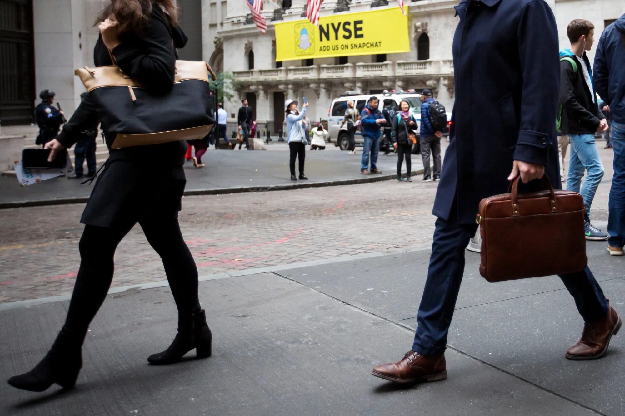 Pedestrians walk along Wall Street in front of the New York Stock Exchange.
