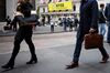 Pedestrians walk along Wall Street in front of the New York Stock Exchange.