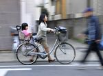 A mother pushes a bicycle carrying her daughter after picking her up from a nursery school in Tokyo.