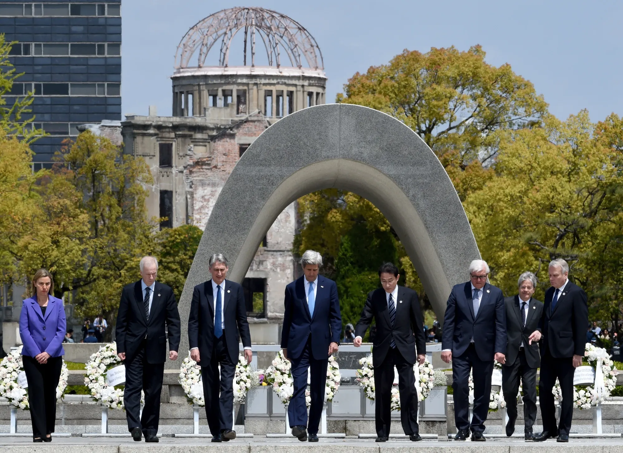 U.S. Secretary of State John Kerry, center, is shown the way by Japan's Foreign Minister Fumio Kishida after laying a wreath at the Memorial Cenotaph for the 1945 atomic bombing victims in the Peace Memorial Park in Hiroshima on April 11, 2016.
