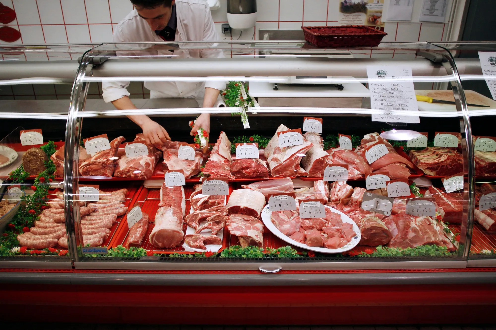 A butcher arranges meat&nbsp;at a supermarket in Herouville Saint-Clair, France.