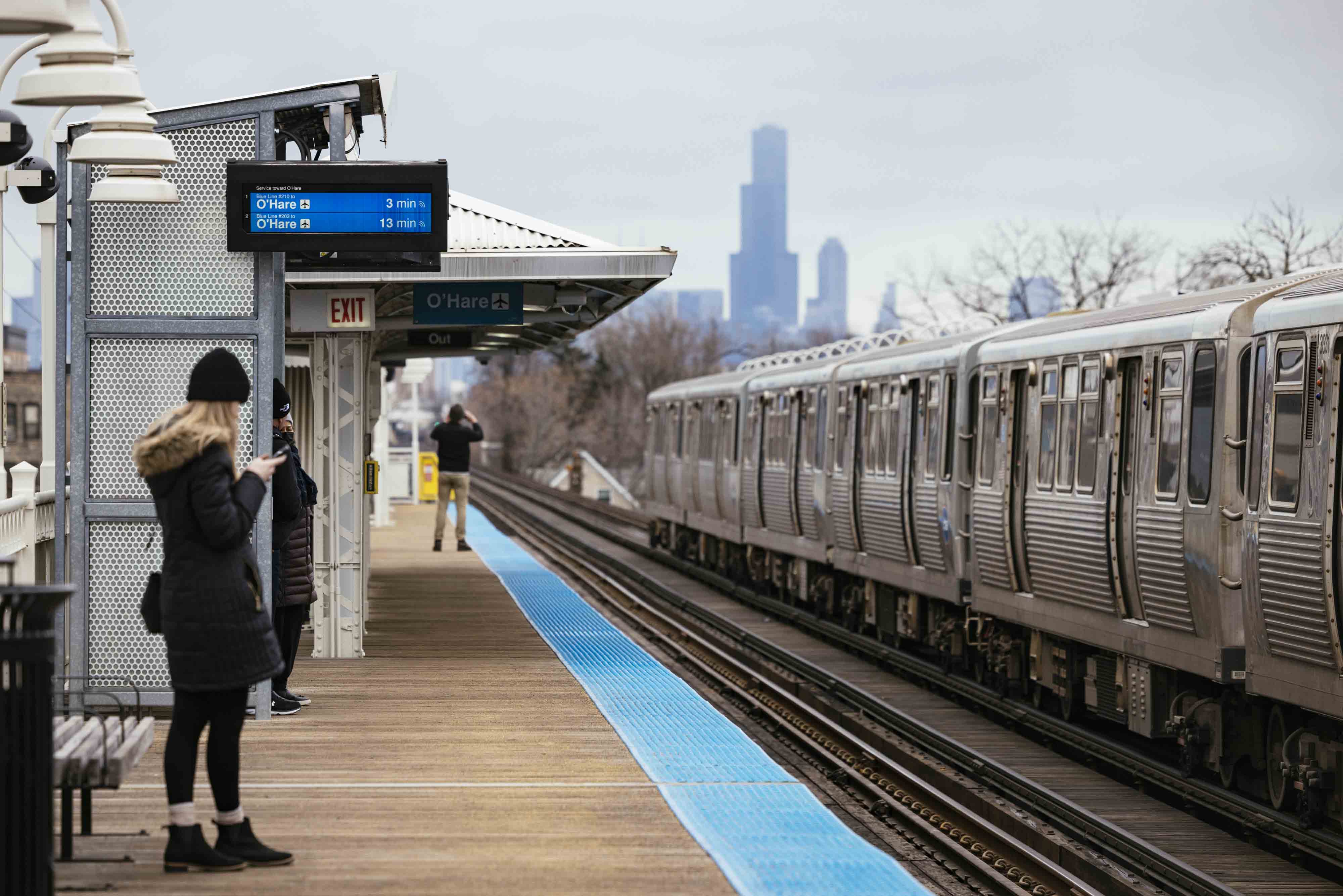 Commuters at the California Blue Line stop in the Logan Square neighborhood of Chicago on Dec. 11, 2022. 