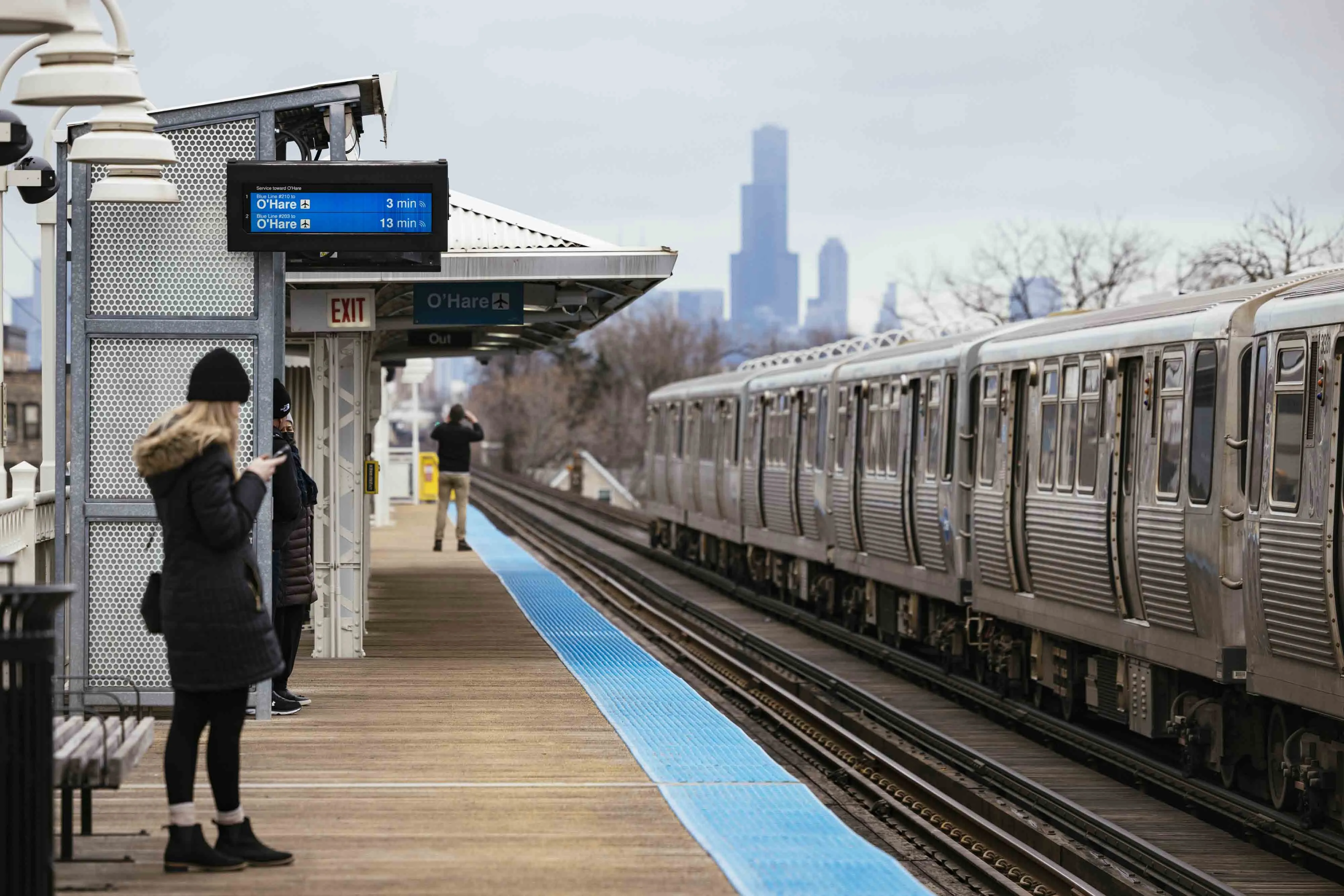 Commuters at the California Blue Line stop in the Logan Square neighborhood of Chicago on Dec. 11, 2022. 