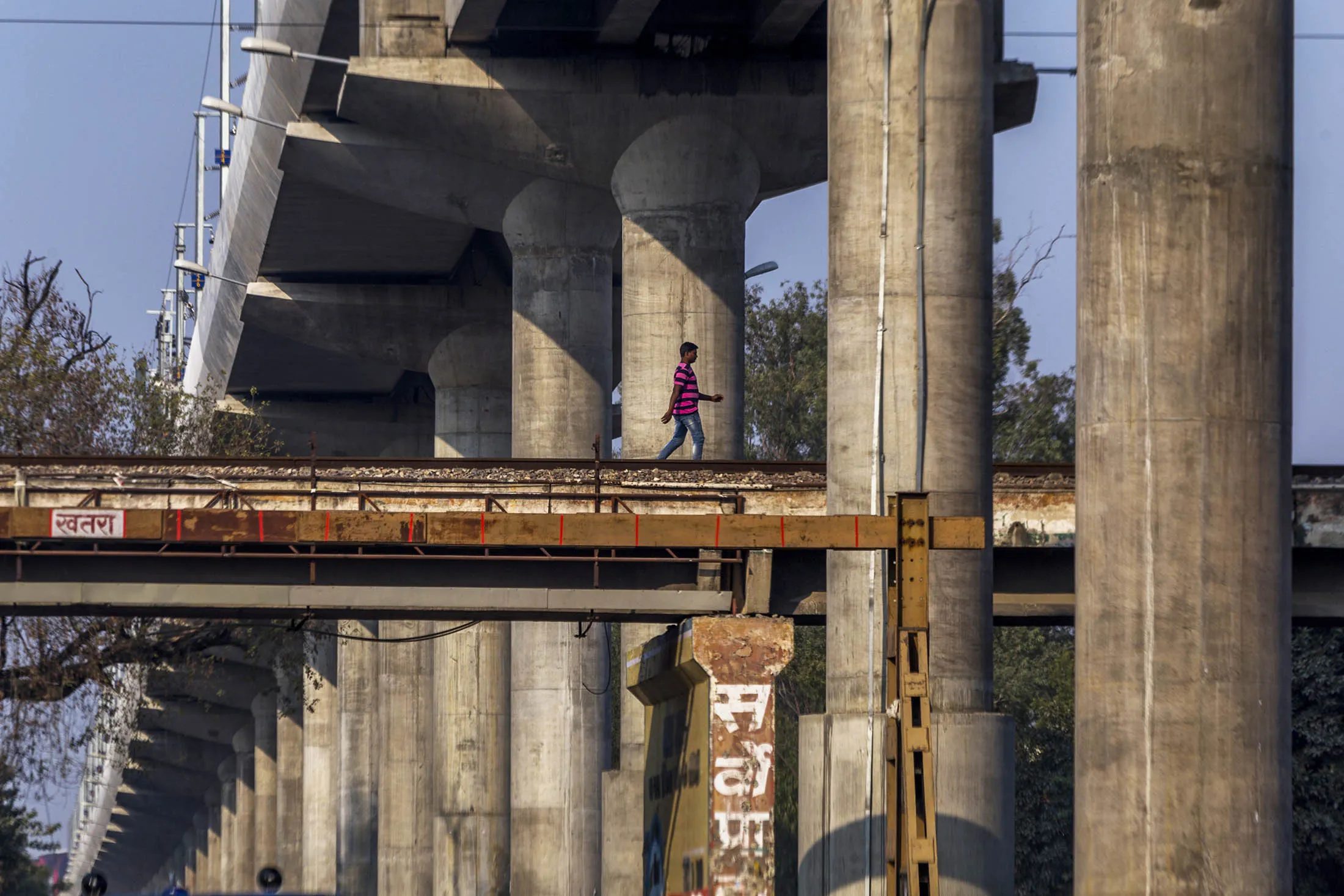 A man walks beneath a on overhead rail track for the Lucknow Metro developed by Lucknow Metro Rail Corp. in the Hazratganj area of Lucknow, Uttar Pradesh, India, on Tuesday, February 14, 2017. The success of the Samajwadi government's infrastructure projects has allowed them to hijack Indian Prime Minister Narendra Modi's mantra of development. Now it's possible the Bharatiya Janata Party (BJP) could lose India's most important state election, that began on Feb. 11., endangering further economic reforms and sapping Modi's momentum ahead of the 2019 national elections.
