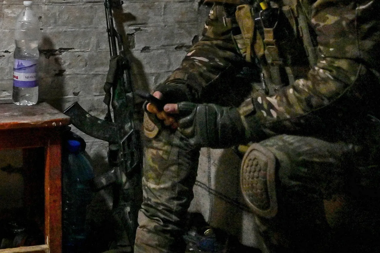A Ukrainian serviceman browses a smartphone at a front line position.