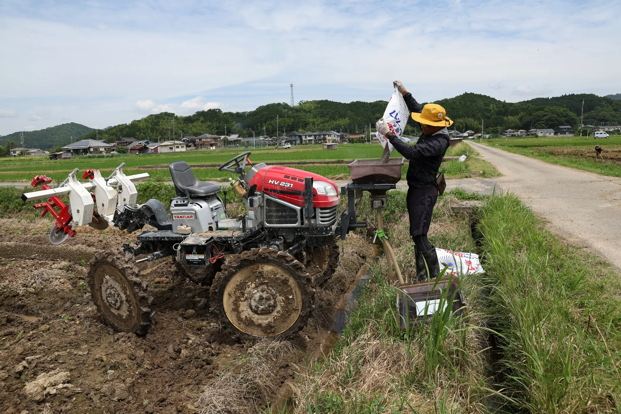 A farmer fills fertilizer into a tractor in Japan.