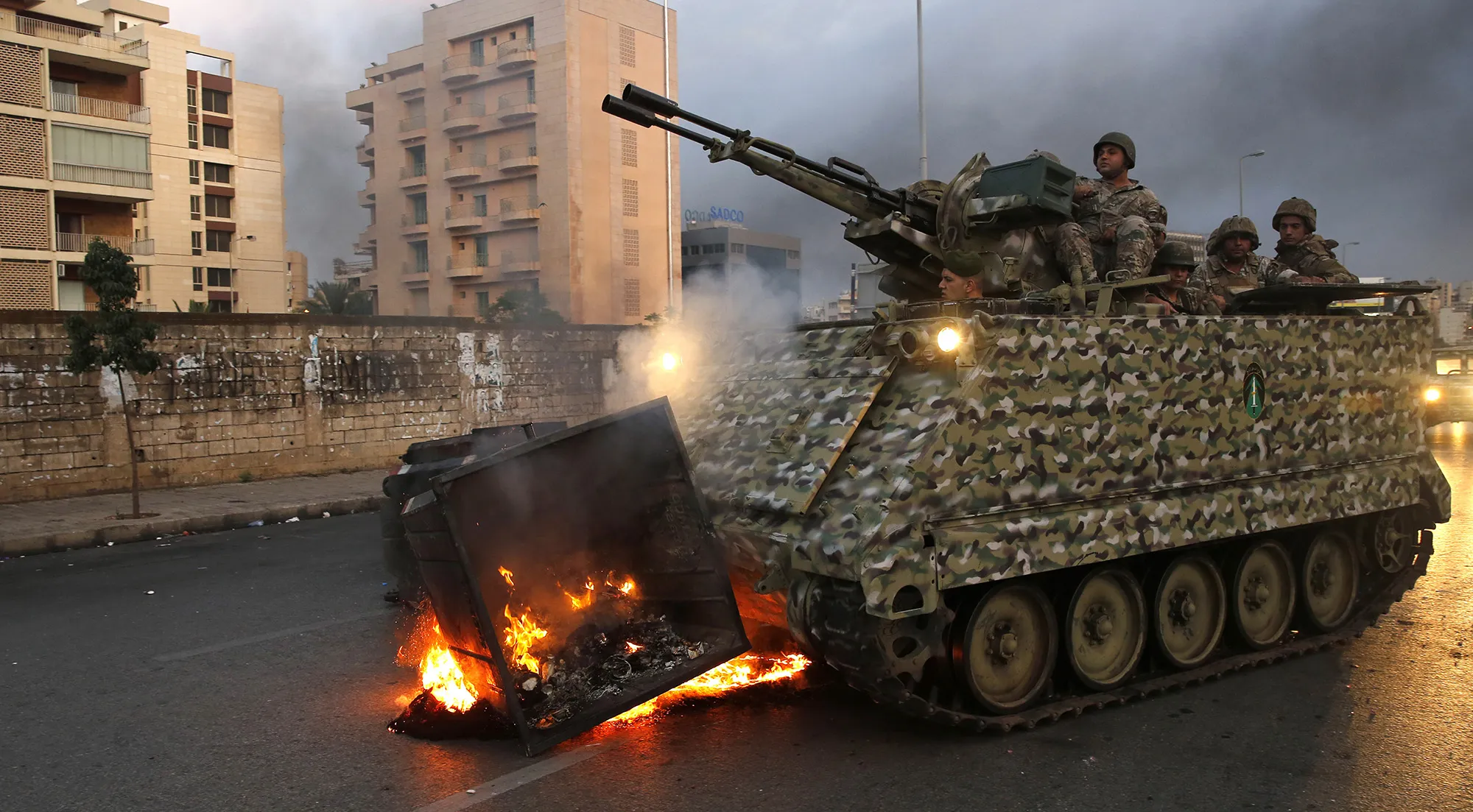 An army armored personnel carrier removes a garbage container set on fire by protesters in Beirut on&nbsp;Oct. 28.&nbsp;