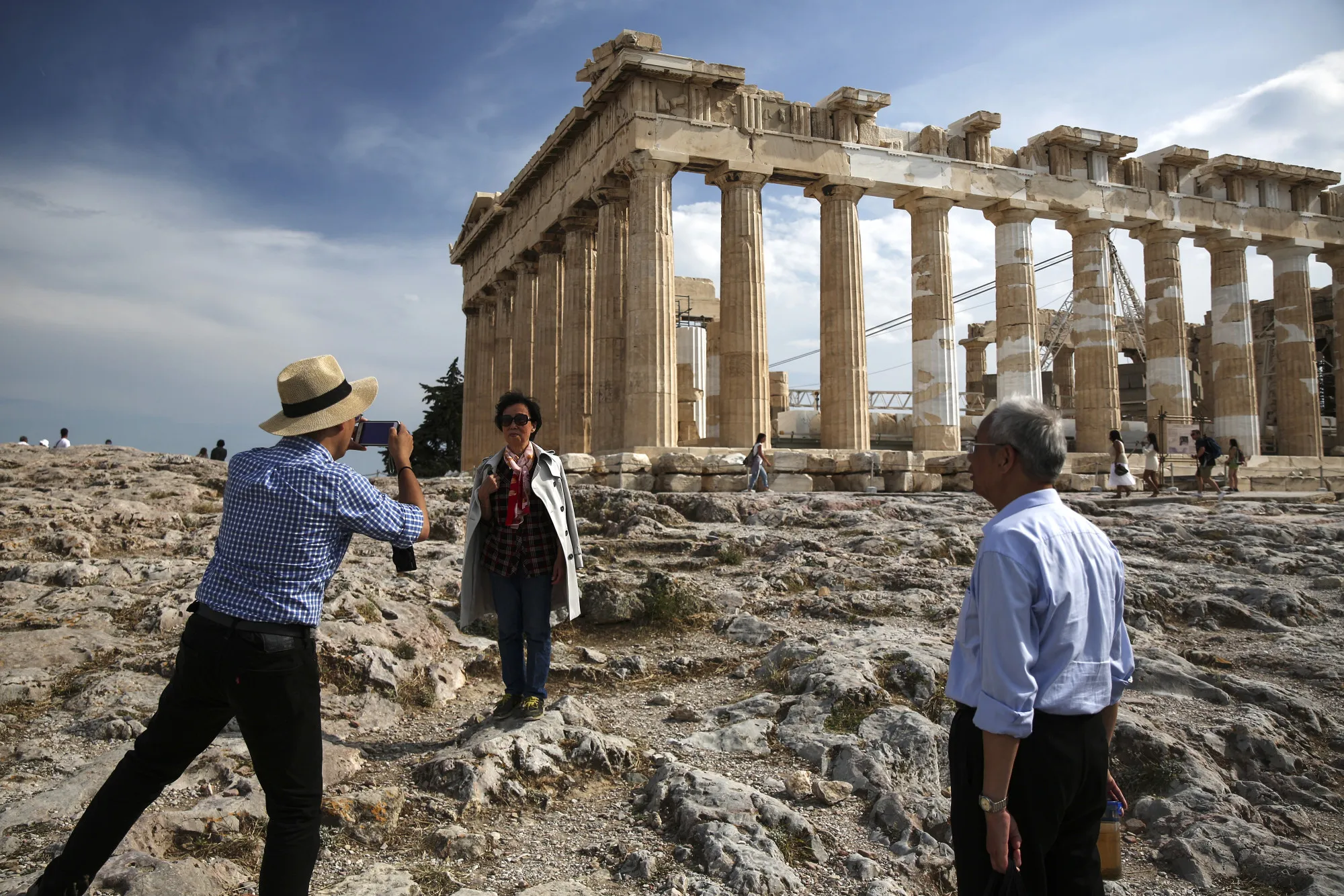 Tourists take photographs in front of the Parthenon temple during a visit at the Acropolis archaeological site in Athens.