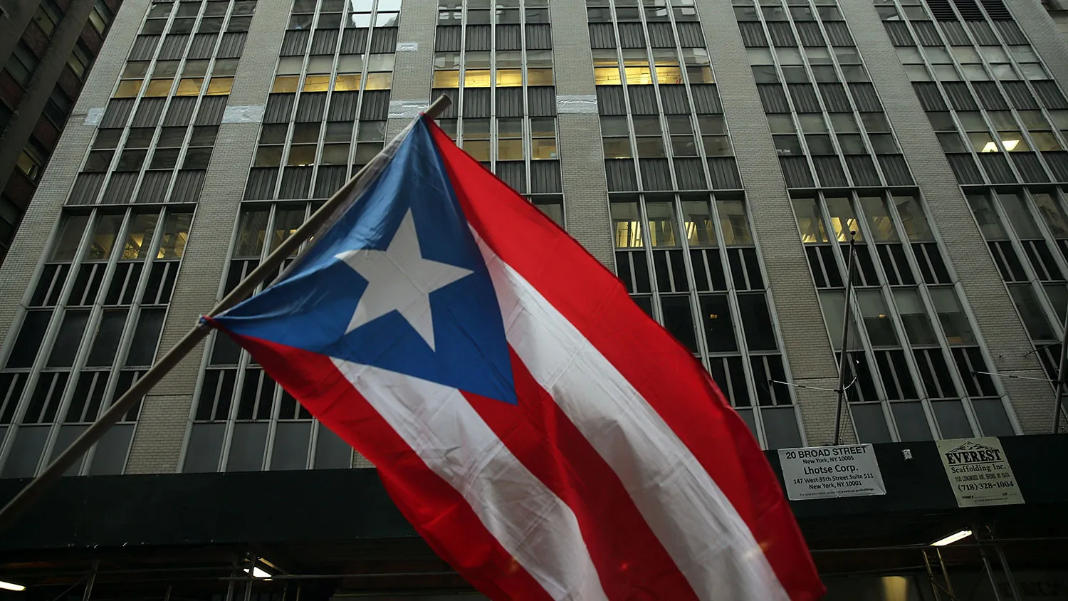 The Puerto Rican flag flies as people protest outside Wall Street against cutbacks and austerity measures on Dec. 2, 2015, in New York City.
