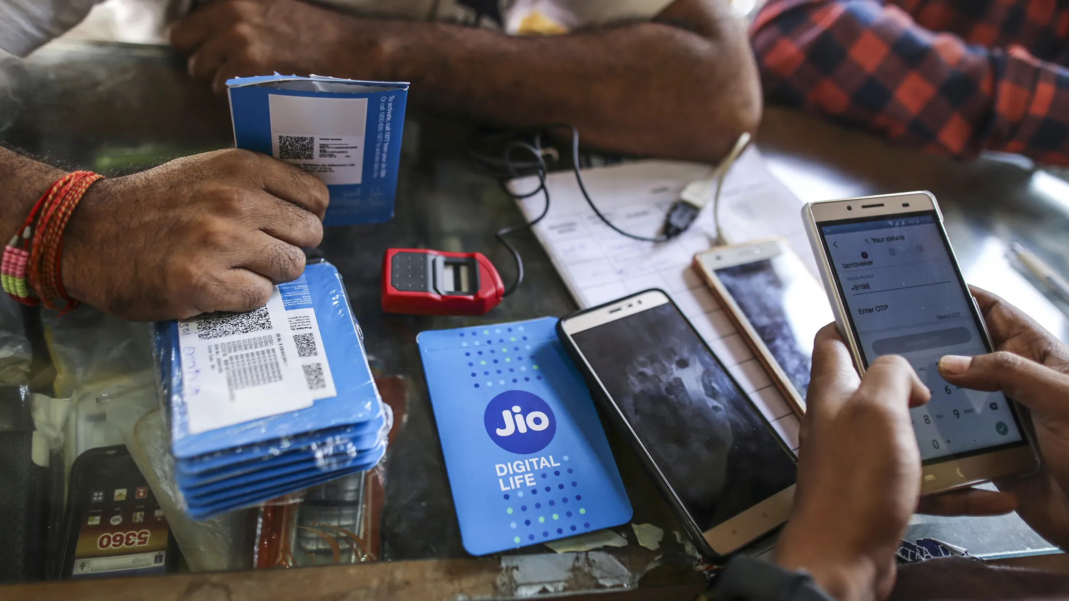 A customer holds a SIM card packet while waiting to connect his mobile phone to the carrier Reliance Jio, the mobile network of Reliance Industries Ltd., at a mobile phone store in Mumbai, India, on Monday, Oct. 24, 2016. Mukesh Ambani's Reliance Industries began offering mobile services last month under the Jio brand.
