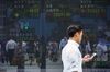 A pedestrian walks past an electronic stock board outside a securities firm in Tokyo, Japan, on Tuesday, June 12, 2018.