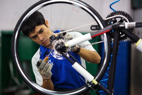 An employee screws parts to a wheel frame of a bicycle on the assembly line of the Giant manufacturing facility in Taichung.