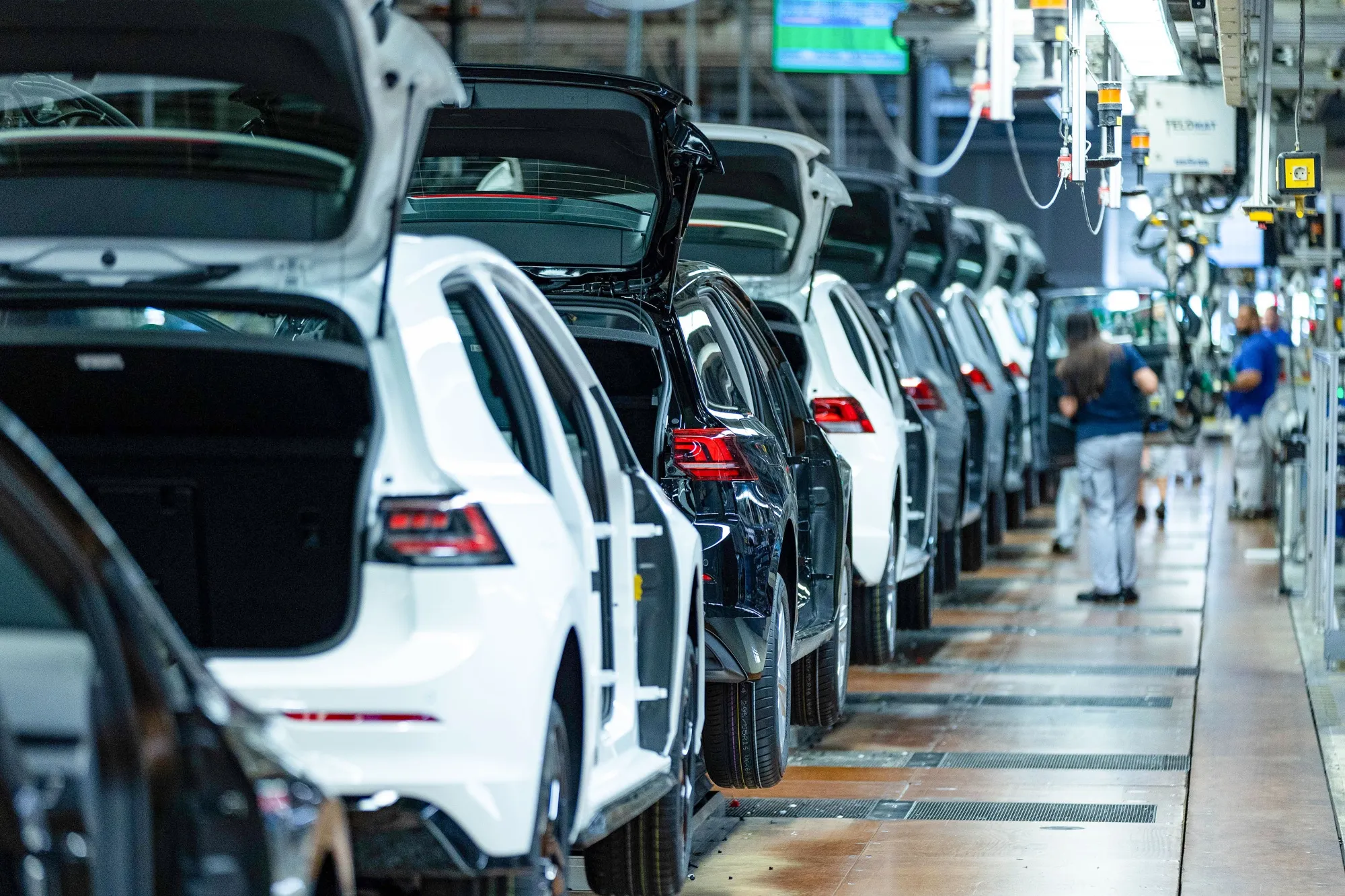 Workers fit car doors to VW Golfs on the assembly line at the Volkswagen AG factory in Wolfsburg, Germany in 2024.