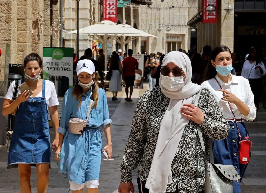 People waer masks against the coronavirus as they walk at a market in Jerusalem.
