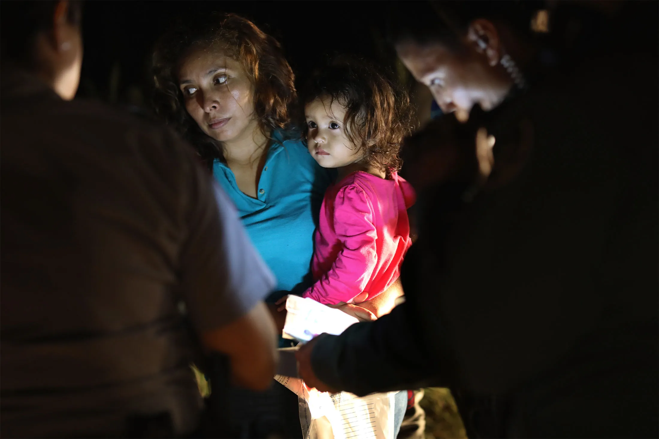 A Honduran mother holds her two-year-old as U.S. Border Patrol&nbsp;agents review their papers near the U.S.-Mexico border on June 12, in McAllen, Texas.