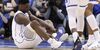 Duke's Zion Williamson sits on the floor following an injury during the first half of an NCAA college basketball game against North Carolina.