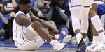 Duke's Zion Williamson sits on the floor following an injury during the first half of an NCAA college basketball game against North Carolina.