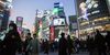 Pedestrians cross an intersection at dusk in the Shibuya district of Tokyo.