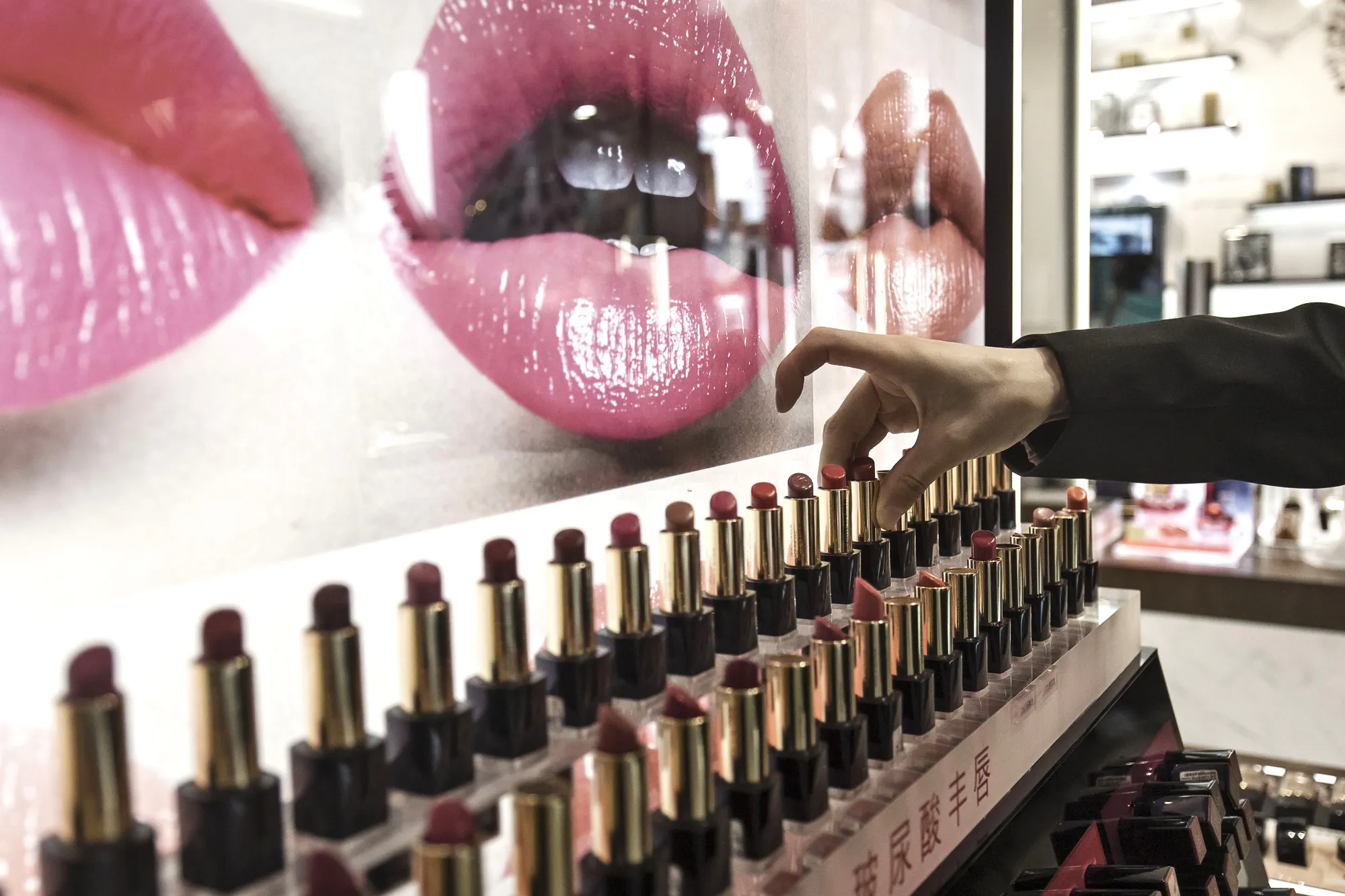 A sales assistant arranges lipsticks at an Estee Lauder Companies Inc. store in the Raffles City shopping mall in Shanghai, China, on Wednesday, May 31, 2017.